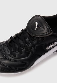 Botín de fútbol Puma King de cuero negro con cordones negros, logotipo de Puma en blanco en la lengüeta y la marca "KING" en blanco en el costado.