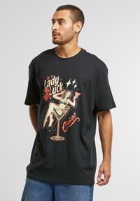 Tricou negru din bumbac cu un grafic retro al unei femei într-un pahar de martini, având textul "Lady Luck Casino" cu accente roșii și galbene.