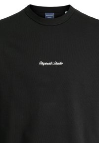 Zwarte sweatshirt van zachte katoen, met een ronde hals en witte borduursel "Originals Studio" gecentreerd op de borst. Eenvoudig ontwerp.