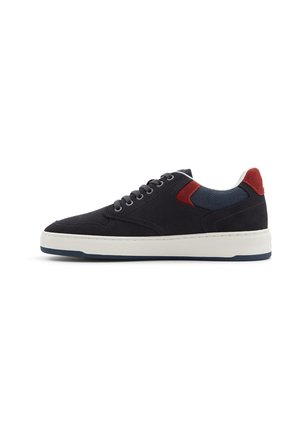 Baskets en suède noir avec un panneau accent texturé bleu marine et rouge, semelle blanche et lacets plats. Design bas adapté pour une utilisation décontractée.