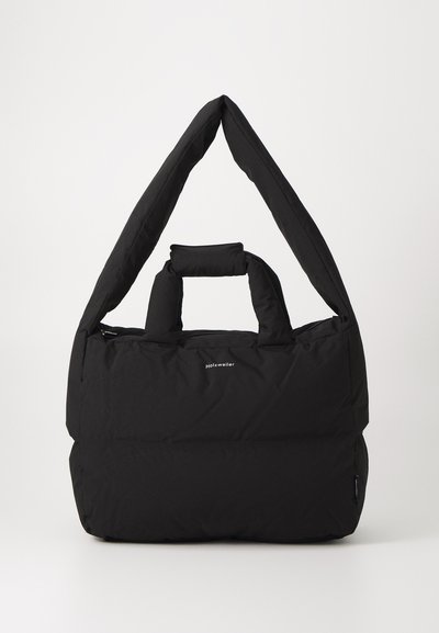 Schwarze gepolsterte Tasche mit einem breiten, weichen Schultergurt und einem oberen Griff. Sie verfügt über einen Reißverschluss und ein dezentes Logo auf der Vorderseite.