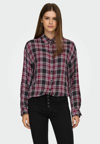 Röd och svart rutig skjorta med knappar och långa ärmar, tillsammans med högmidjade svarta jeans med fem knappar. Slät tygkvalitet.