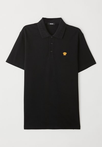 Melna polo krekls, kas izgatavots no kokvilnas, ar trīs pogu aizdari un zeltītu Medūzas logo uz krūts daļas. Maiga, gluda tekstūra.