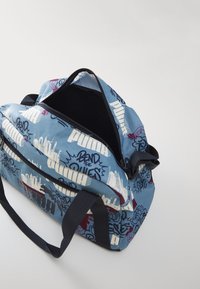 Kék vászontáska, graffiti-stílusú fehér és bordó nyomattal. Cippzárral záródik és fekete bélése van. Fekete pántokkal.