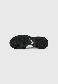 Schwarze Sport-Schlittschuhe mit einer strukturierten Gummisohle, die ein weißes Nike-Logo und ein Zickzack-Griffmuster aufweist. Offenes Design mit flacher Sohle.