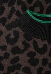 Brązowa dzianina swetra z czarnym nadrukiem w cętki lamparta. Czarny prążkowany kołnierz z zielonymi paskami. Miękka tekstura, widok z bliska.
