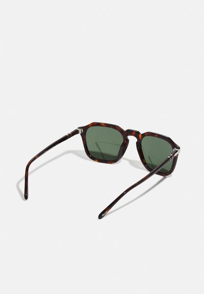 Tortoiseshell sunglasses with octagonal frames and dark green lenses. Thin arms with subtle metal accents. Smooth plastic texture.