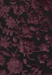 Tamna tkanina s teksturiranim cvjetnim uzorkom u dubokom mauve tonu na crnoj pozadini, koja se odlikuje složenim detaljima i mekanim osjećajem.