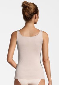 Canottiera beige chiaro realizzata in materiale morbido, con spalline sottili e un design aderente. Presenta una texture liscia e un orlo dritto.