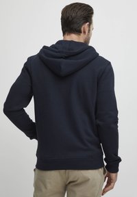Hoodie bleu marine en coton mélangé doux, avec capuche à cordon de serrage et poignets côtelés. Texture lisse avec une silhouette ajustée et une poche kangourou.