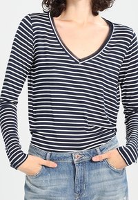 Camicia a maniche lunghe a righe blu navy e bianche con scollo a V profondo. Tessuto morbido, vestibilità rilassata, presenta un colletto a contrasto e una leggera elasticità.