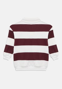 Πλεκτό πουλόβερ με μακριά μανίκια και εναλλασσόμενες οριζόντιες ρίγες σε μπορντό και λευκό. Διαθέτει γιακά και ριμπ μανσέτες. Κατασκευασμένο από μαλακό ύφασμα.