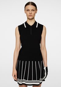Black sleeveless polo top with a white-collared neckline and a quarter zipper, paired with a black-and-white striped skirt. Black glove accessory.