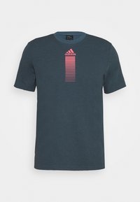 Tmavě modré tričko s krátkým rukávem z bavlny s kulatým výstřihem, na přední straně je vertikální růžové proužkované logo adidas.