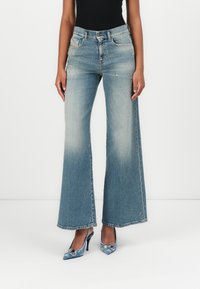 Light blue denim wide-leg jeans with a faded look, featuring five pockets and a button closure, paired with blue pointed-toe heels.