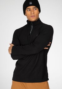 Pullover in pile nero con zip a metà, maniche lunghe e un logo discreto sul petto. Texture calda e morbida, adatta per attività all'aperto.