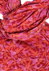 Pink scarf featuring red flower patterns, made of lightweight fabric with a soft texture. It is gathered and twisted for styling.