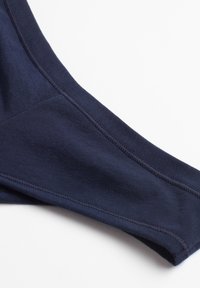 Marineblauwe rekstof met een gladde textuur en platte naden, die een getailleerd ontwerp en een naadloze afwerking langs de randen laat zien.