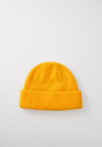 Geltona megzta beanie kepurė su raukšlėta apatine dalimi ir tekstūruotu raštu, su šiek tiek siaurėjančiu apvaliu viršumi. Minkšta medžiaga.