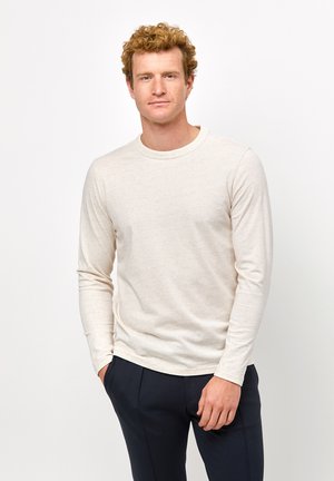 Lys beige langærmet t-shirt lavet af blødt stof, med en rund halsudskæring og en normal pasform. Teksturen synes let meleret.