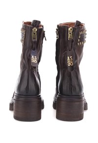 Stivali ankle in pelle marrone con punta rotonda, cerniere laterali e borchie decorative sulla parte esterna dello stivale. Presentano un tacco in legno impilato.