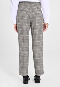 Karierten Hosen mit tailliertem Schnitt, in Grau- und Schwarz-Tönen, mit geraden Beinen und glatter Textur. Getragen mit einem weißen Hemd und schwarzen Schuhen.