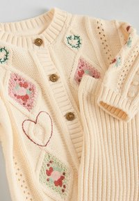 Lyscremet strikket cardigan med broderede blomstermønstre i pink og grøn, med træknapper og ribbede detaljer.