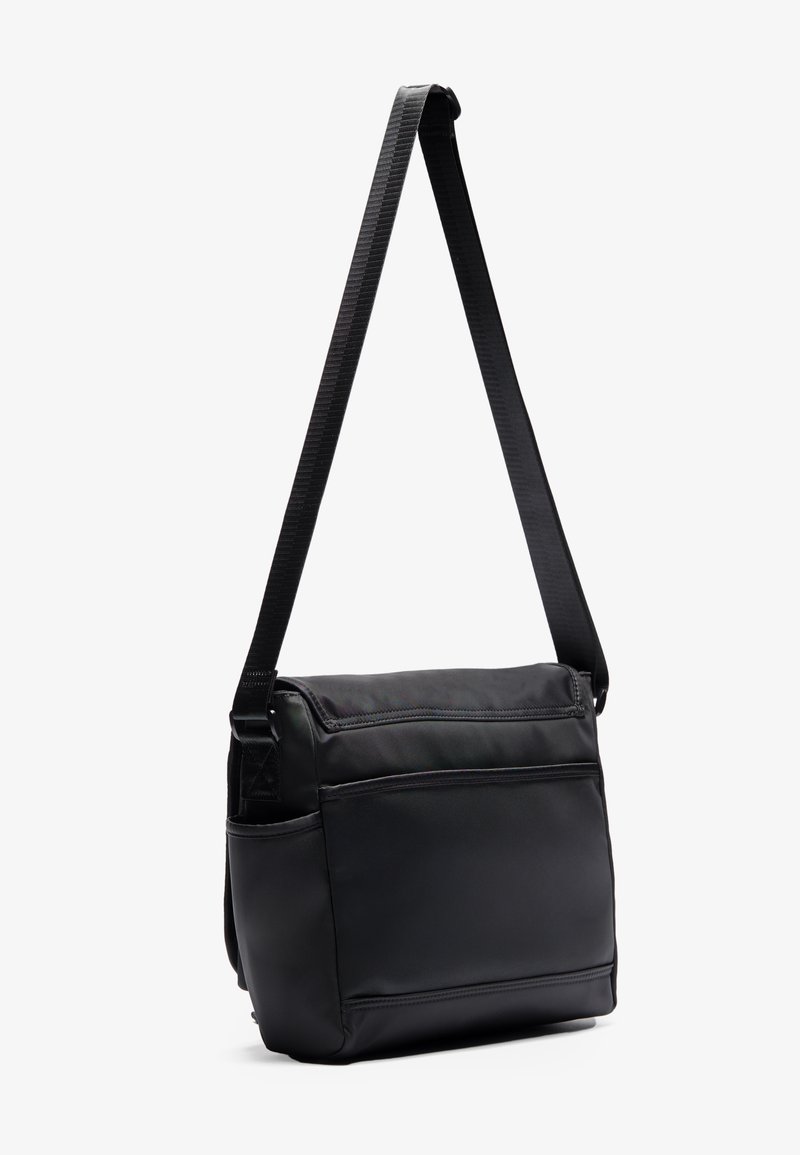 Bolso cruzado negro hecho de nylon suave con una correa tejida ajustable, que cuenta con múltiples bolsillos exteriores y una forma rectangular elegante.