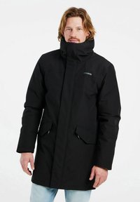 Parka nera con colletto alto, cerniere e due tasche frontali. Realizzata in un materiale morbido e resistente. Design semplice e funzionale.