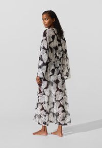 Garšs, caurspīdīgs kimono ar melnbaltu lapu rakstu, kuram ir plašas piedurknes un josta viduklim. Audumam ir viegla, gluda tekstūra.