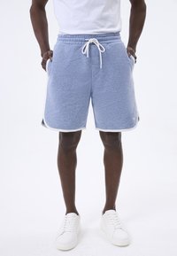 Pantalones cortos deportivos de color azul claro con una cintura elástica y cordón, bolsillos laterales y ribete blanco en el dobladillo. Hechos de una tela suave y texturizada.