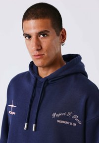 Marineblauwe hoodie van katoenmix, met een capuchon met trekkoord, zilveren hardware-accenten en geborduurde logo's in het roze aan de voorkant.