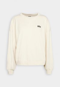 Sweat-shirt à manches longues couleur crème avec poignets et ourlet côtelés, col rond, et petit logo "GAP" noir sur la poitrine gauche.