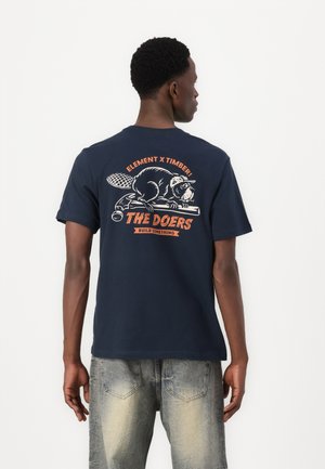 Dunkelblaues T-Shirt aus Baumwolle mit einem Biber-Print auf der Rückseite in Orange und Weiß, versehen mit dem Text "THE DOERS" und "ELEMENT X TIMBER!"