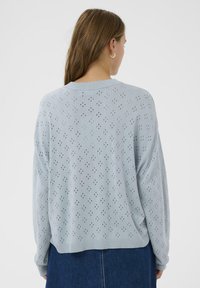 Sweater en tricot bleu clair avec un motif ajouré, des manches larges et une coupe décontractée. Fini avec un col et un ourlet côtelés.