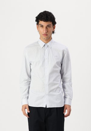 Camisa de manga larga a rayas blancas y azul claro con cuello abotonado. Presenta un logotipo en el pecho y una tela suave y ligera.