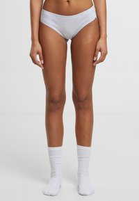 Szürke pamut bikini alsó, sima derékkal, minimális varrásokkal és klasszikus szabással. Fehér bordázott bokazoknival viselve.