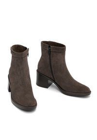 Brown suede ankle boots with a subtle heel, featuring a zip closure on the outer side and a rounded toe design.