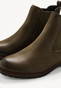 Bottines en cuir marron avec des panneaux élastiques sur les côtés, bout rond, texture lisse et coutures contrastantes le long de la semelle.