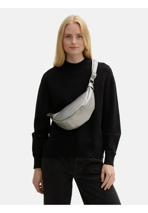 Marsupio argento metallico con finitura in pelle texturizzata, caratterizzato da una forma curva e una tracolla regolabile, indossato a tracolla su un maglione nero.