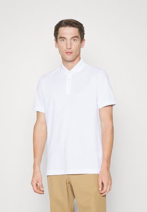 Weißes Polo-Shirt mit kragenloser Halslinie und kurzen Ärmeln, aus strukturiertem Baumwollstoff mit einem dezenten Logo-Detail auf der Brust.