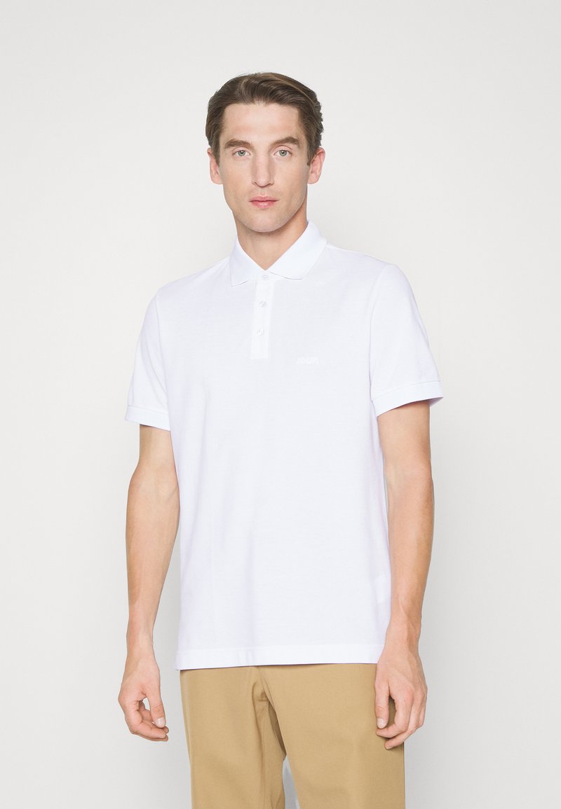 Weißes Polo-Shirt mit kragenloser Halslinie und kurzen Ärmeln, aus strukturiertem Baumwollstoff mit einem dezenten Logo-Detail auf der Brust.