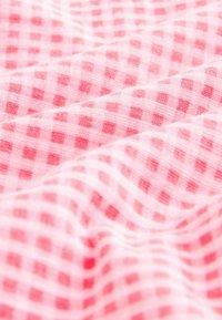 Tissu doux avec un motif vichy rose et blanc, présentant des petits carreaux étroitement espacés et de légers plis.