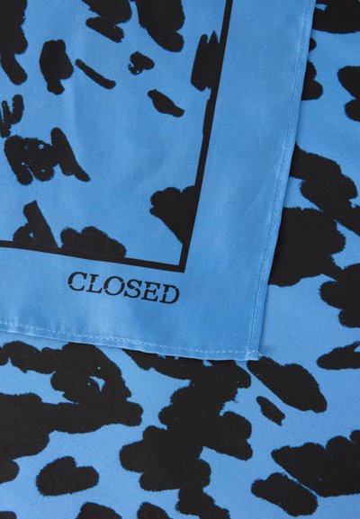 Tissu bleu avec des taches abstraites noires et un bord cousu, avec le mot « CLOSED » imprimé près du coin.