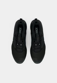 Ein Paar schwarze Adidas Terrex Trailrunningschuhe mit Schnürsenkeln, von oben auf einem weißen Hintergrund betrachtet.
