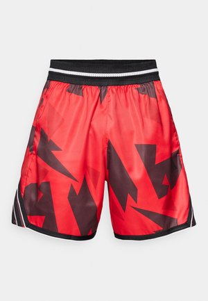 Pantaloni sportivi rossi con un motivo astratto nero, vita elastica con strisce bianche e nere, realizzati in materiale lucido e leggero.