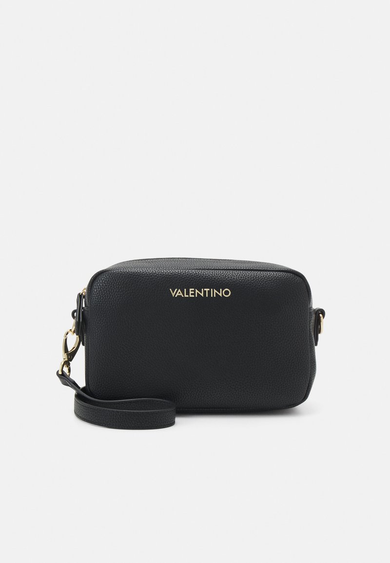 Bolsa transversal em couro preto com textura granulada, logótipo da marca em dourado, alça ajustável e fecho com zíper. Design compacto e rectangular.