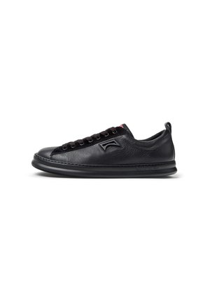 Black leather sneaker with rounded toe, textured side panels, and flat laces. Features a padded collar and a sleek rubber sole.