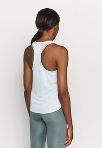 Ljusblå atletisk linne med racerback-design, gjort av fukttransporterande tyg, med en logotyp på ryggen och platta sömmar.