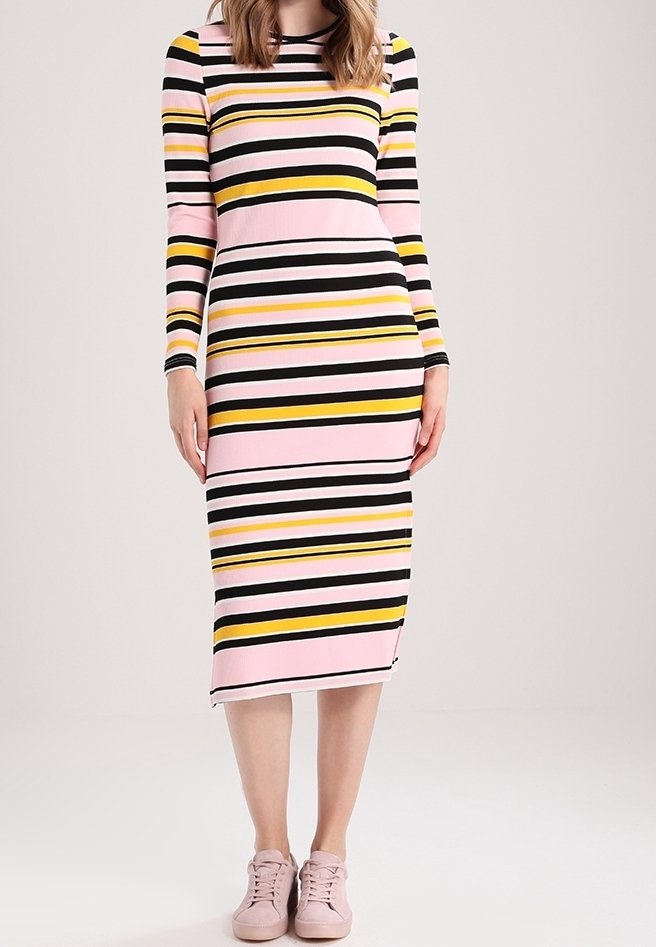 Abito a maniche lunghe con strisce orizzontali in rosa, nero e giallo. Vestibilità slim e lunghezza al ginocchio, abbinato a sneakers rosa chiaro.